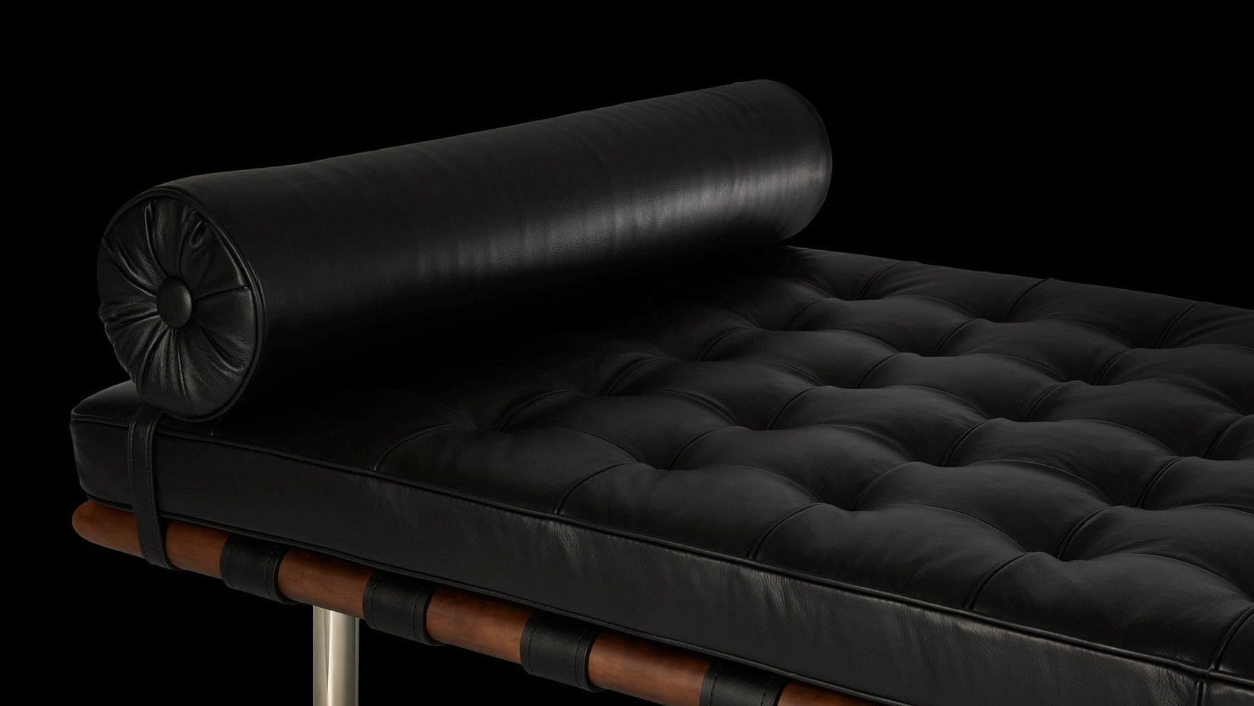 The flicker of light is all that illuminates a Van Der Rohe Barcelona Daybed with dark black leather against the dark backdrop of this banner photograph