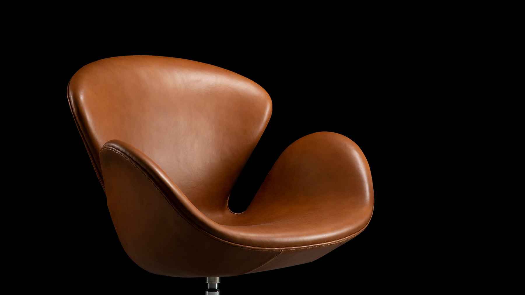 A solitary light from afar catches the top of and illuminates the tan leather of the Arne Jacobsen Swan Chair in this beautiful banner photograph image