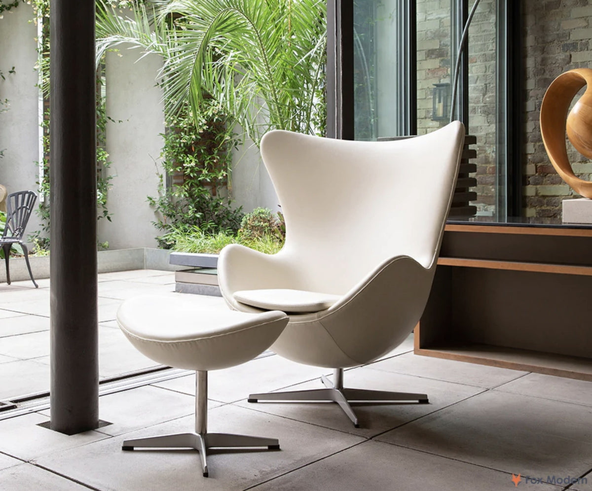 Front angled view of white leather Jacobsen Egg chair and ottoman in a living space
