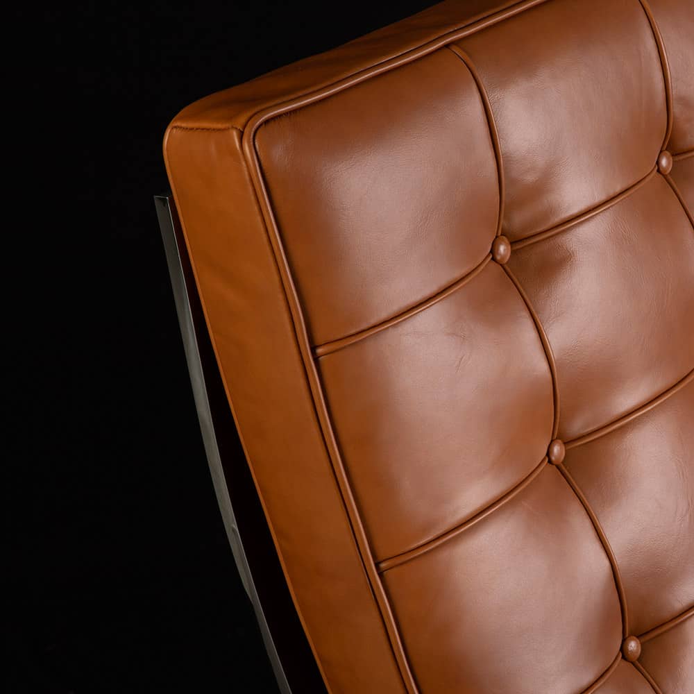 Close up front view of the tan leather Barcelona Chair on black background