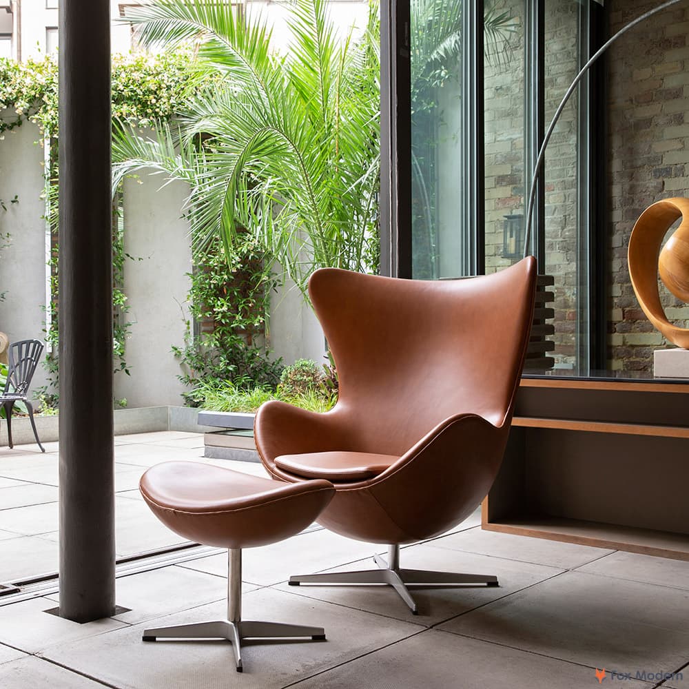 Front angled view of tan leather Jacobsen Egg Chair & Ottoman shown in a living space