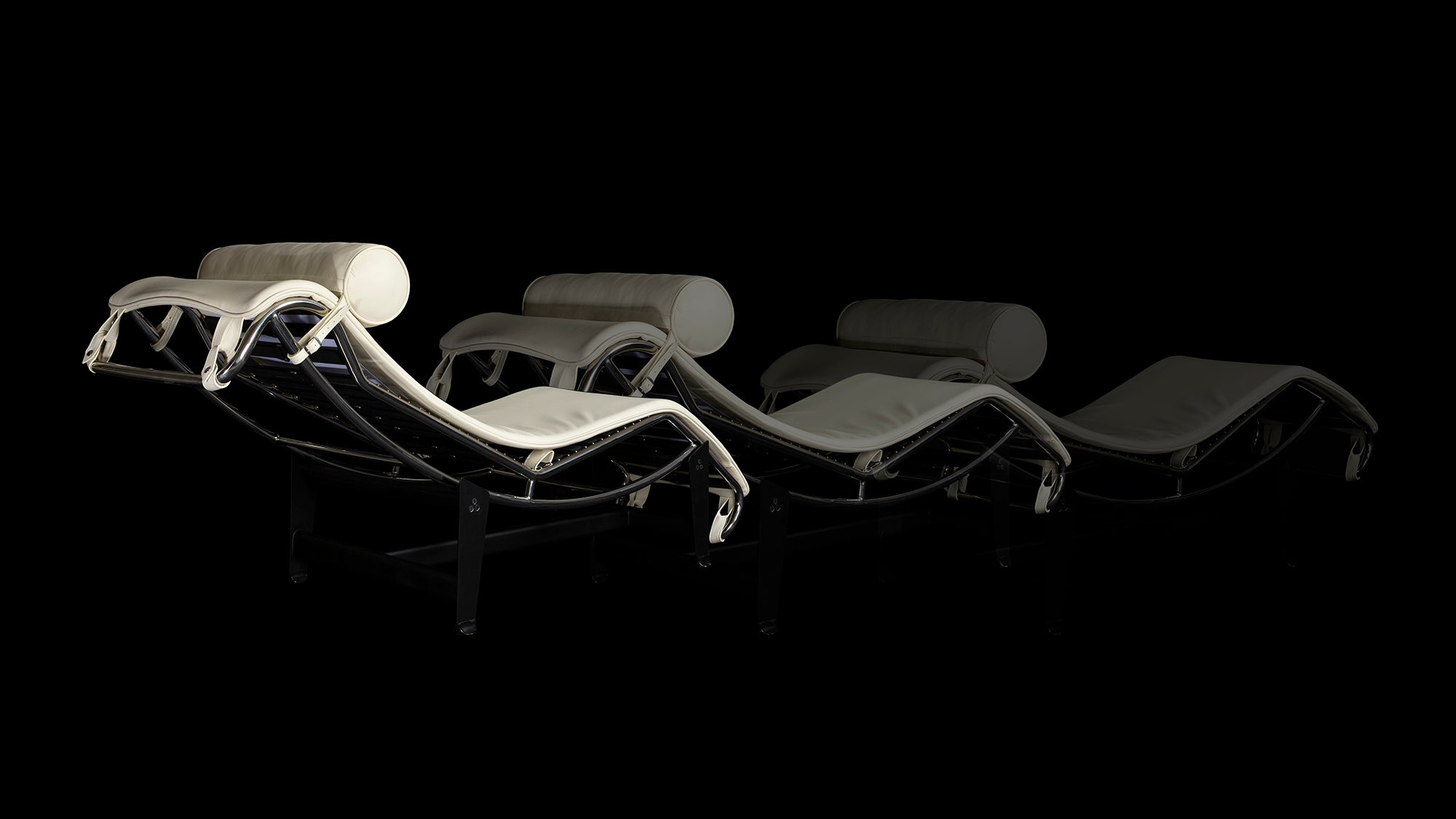 The Corbusier LC4 Chaise Longue in white is seen ghosting across the black background