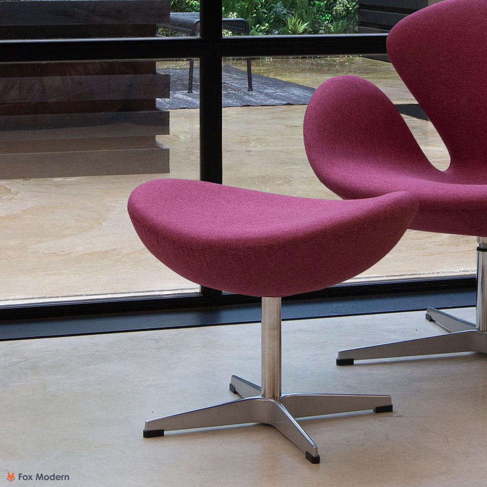 Angled view of pink fabric Arne Jacobsen ottoman shown in a living space