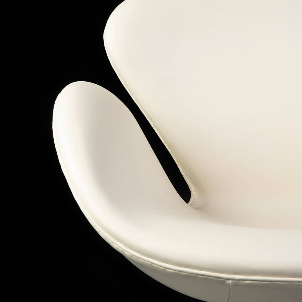 Close up front view of white leather Arne Jacobsen Swan Chair on a black background