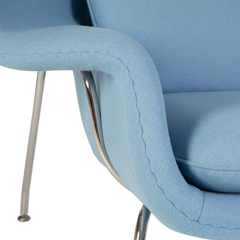 Close up view of corner of the blue fabric Saarinen Womb chair on a white background