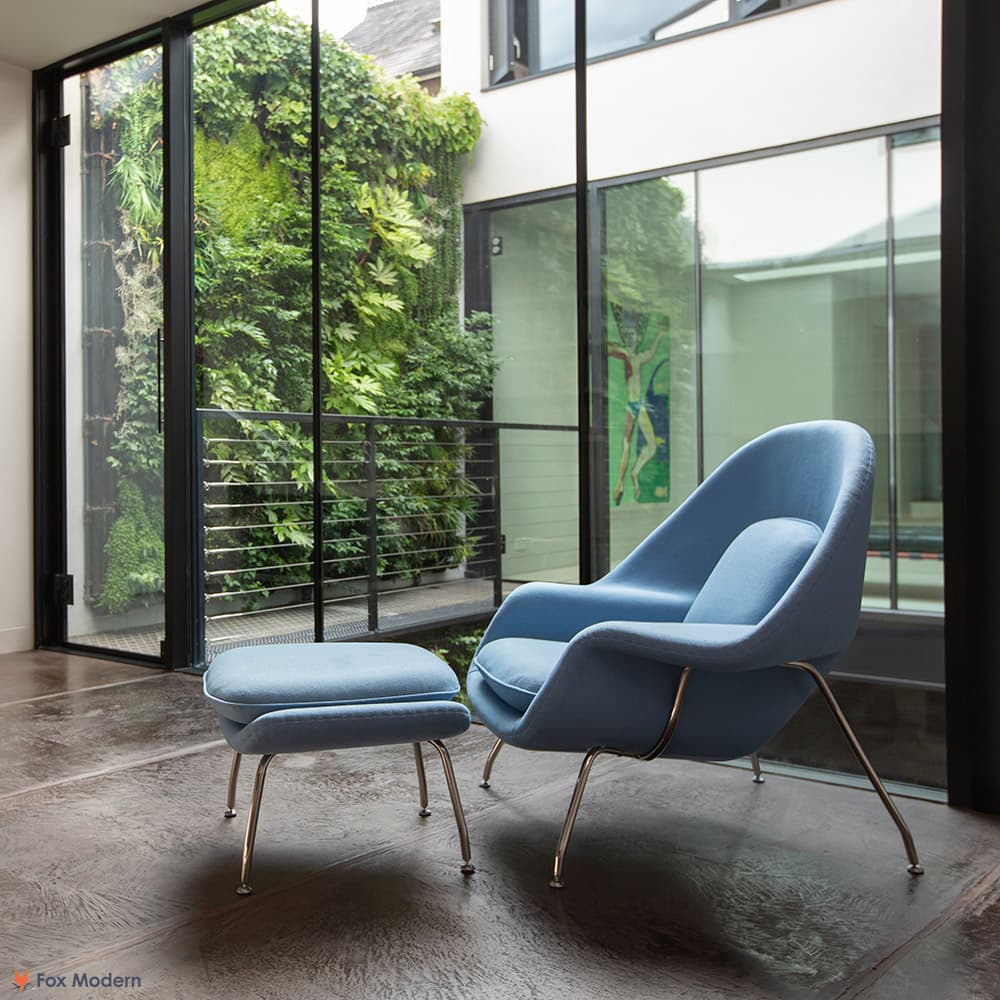 Front angled view of blue fabric Saarinen Womb Chair & Ottoman shown in a living space