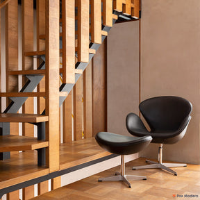 Angled front view of black leather Jacobsen Swan Chair & Ottoman shown in a living space