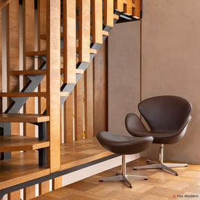 Angled front view of brown leather Jacobsen Swan Chair & Ottoman shown in a living space