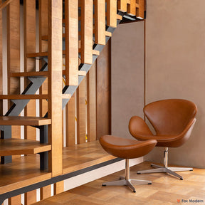 Angled front view of tan leather Jacobsen Swan Chair & Ottoman shown in a living space